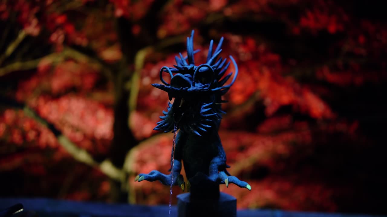 Fontana del drago in un tempio giapponese di notte con aceri rossi autunnali