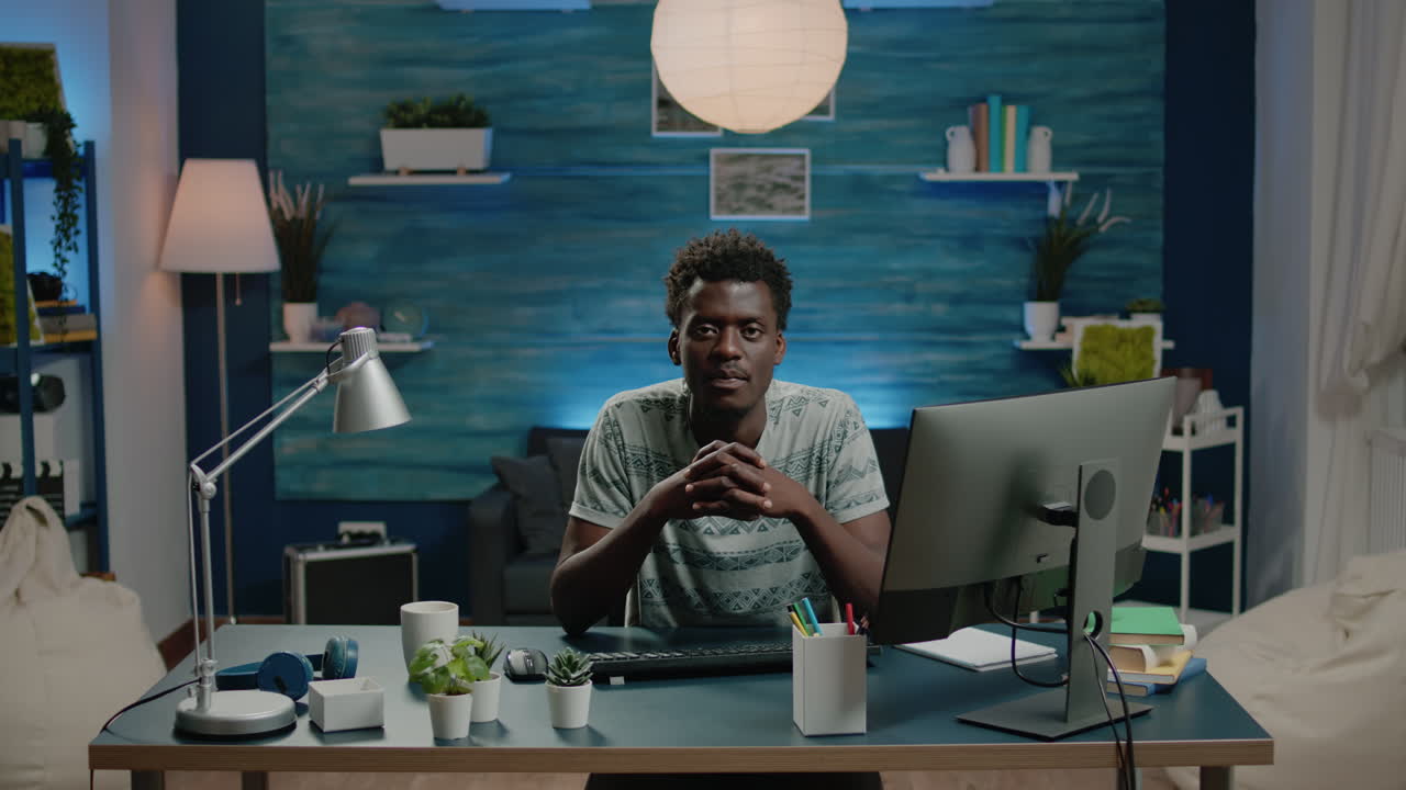 Portrait of black adult sitting at desk with computer