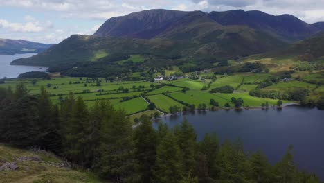 aerial drone video of incredible scenery over lake buttermere with forest in foreground and mountains in background on a cloudy sunny day