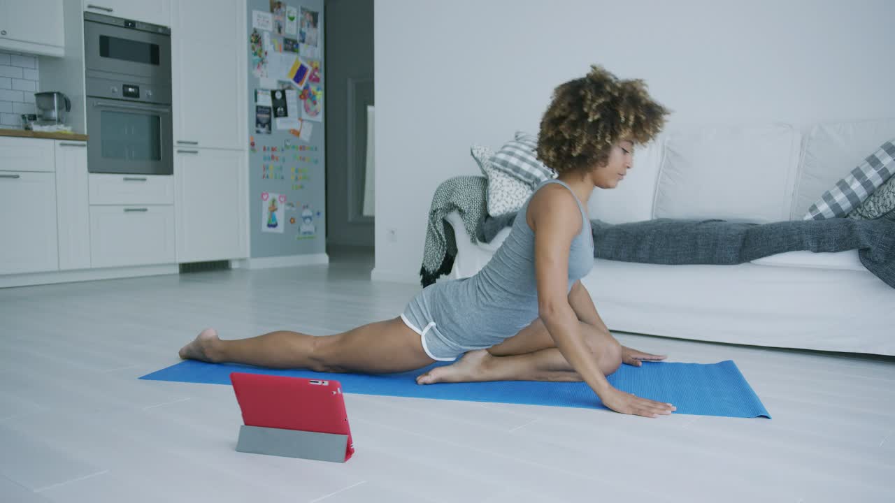 mujer joven practicando yoga viendo tutorial