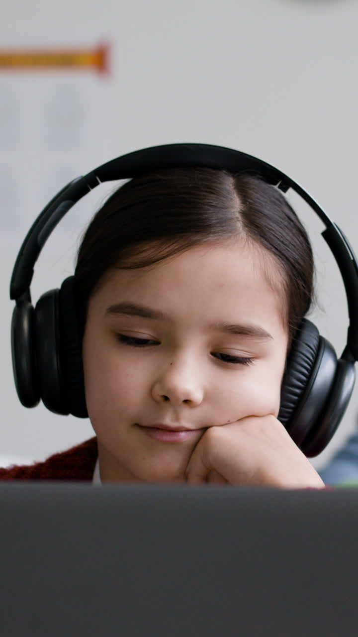 Young girl studying on a laptop with headphones