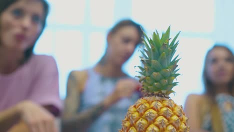 fresh pineapple with bright green top against blurred women