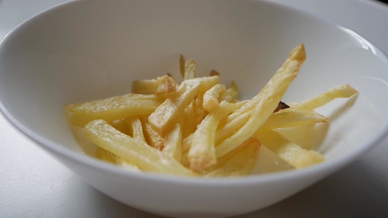 Cose-up view of a caucasian hand taking french fries from a plate