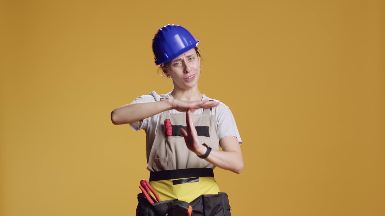 Portrait of woman contractor showing t shape sign in studio