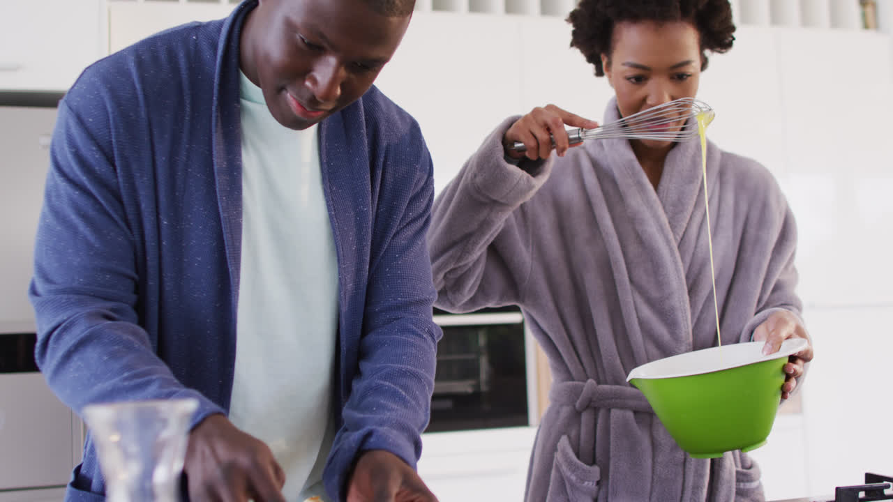 Video of happy african american couple preparing breakfast together in kitchen