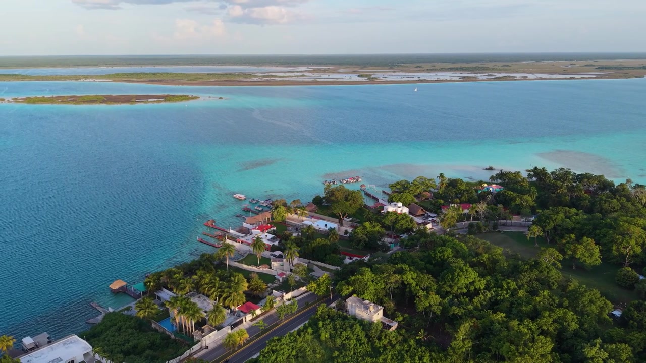 Private piers extend from lush green coastal vegetation into shallow blue shallows.