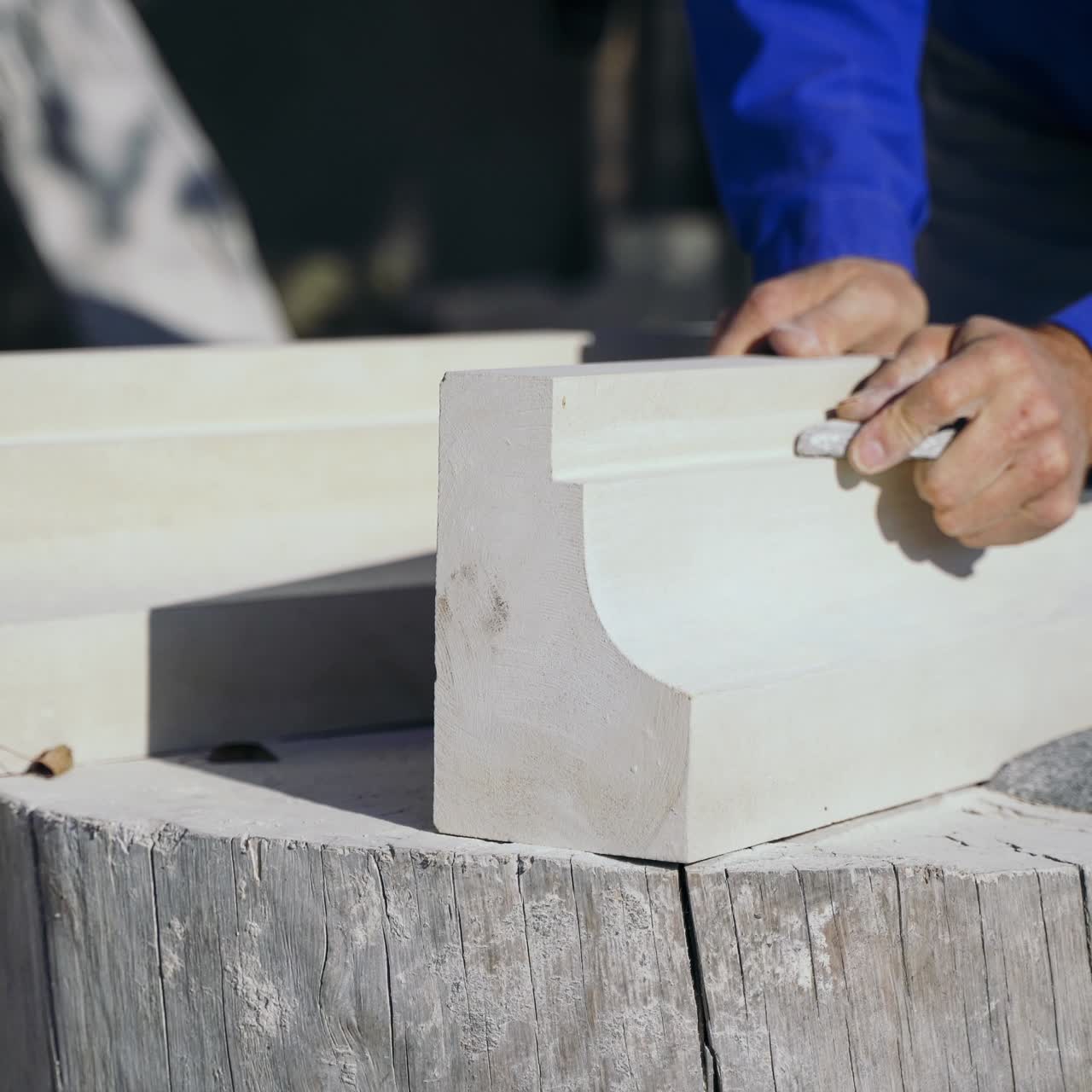 carpenter is polishing a wooden column in the courtyard in the street. Woodworking.