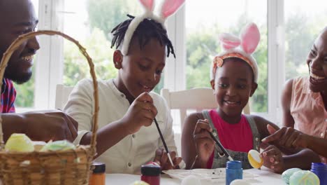 african american family painting easter eggs together at home