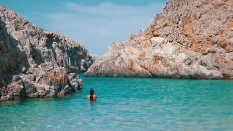 Girl-emerging-from-turquoise-waters-in-a-cove-beach