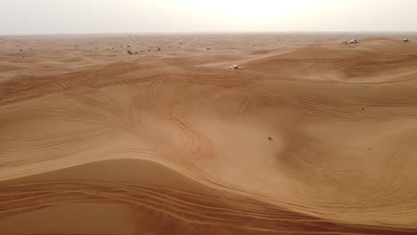 Aerial-view-of-cars-driving-over-the-dunes-in-the-Dubai-desert
