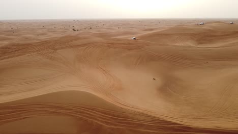 aerial view of cars driving over the dunes in the dubai desert