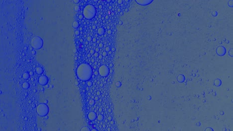 flujo de aceite azul sucio con manchas negras lentamente con burbujas y polvo en la superficie