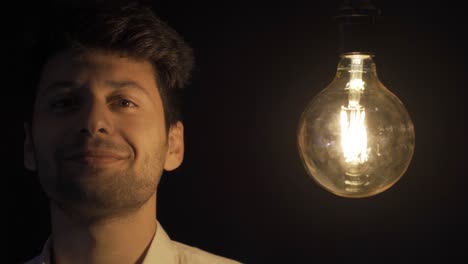 the man touches the lamp with his finger, which means he has an idea. eureka.