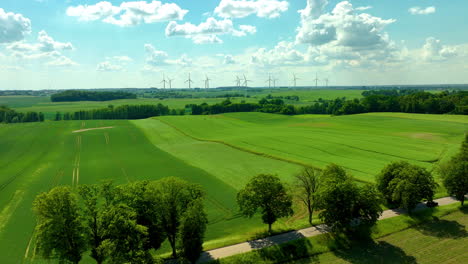 Aerial-rural-landscape-scene-features-expansive-green-fields-under-a-bright-blue-sky-with-scattered-clouds