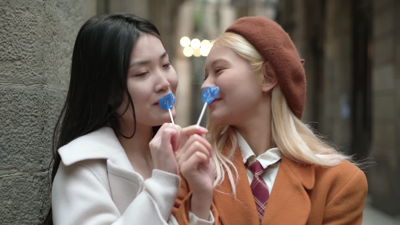 Two young women enjoying lollipops together