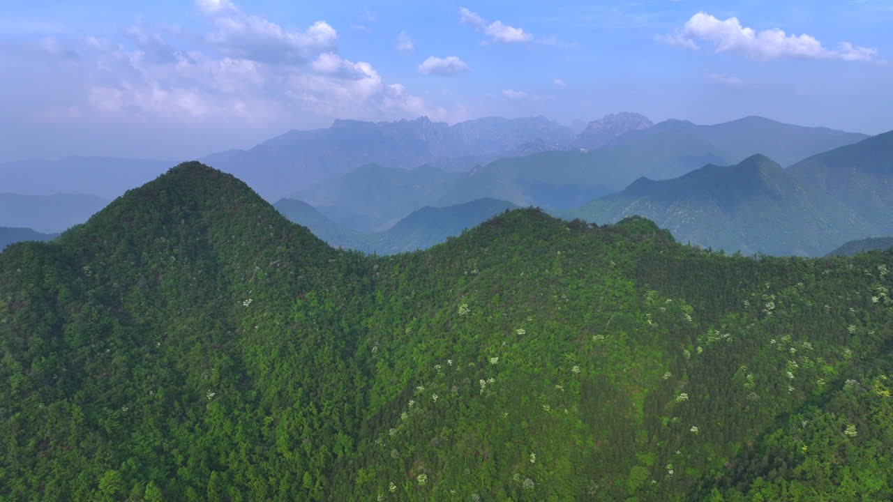 Aerial photography of high mountains shrouded in clouds and mist after rain, humid climate, and green forests shrouded in mist