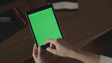 mano femenina usando una tableta de pantalla verde. mujer de negocios tocando la pantalla de la tableta