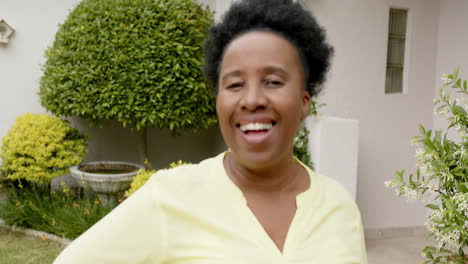 Happy-african-american-senior-woman-with-curly-hair-laughing-in-sunny-garden,-slow-motion