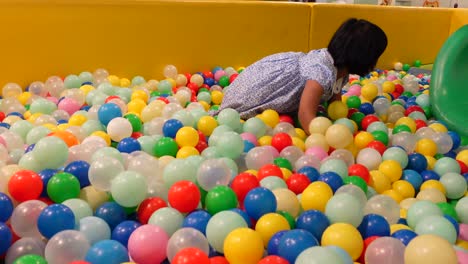 niño jugando en un pozo de pelota colorido