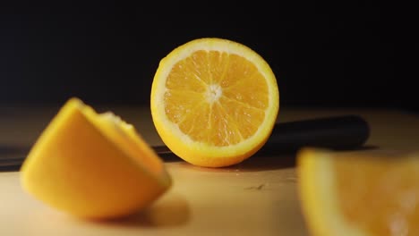 freshly cut orange fruit with knife laying on the table with black screen background