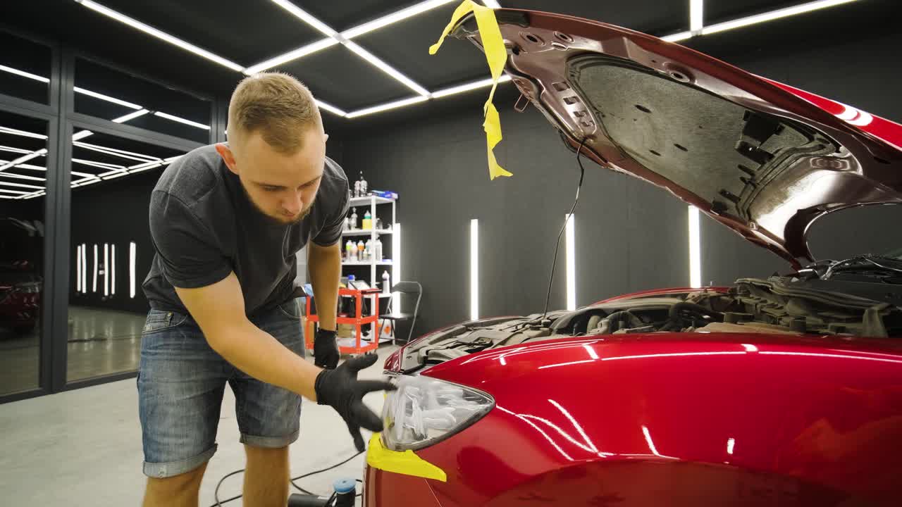 trabajador de servicio de automóviles aplicando nano recubrimiento en un detalle de automóvil.