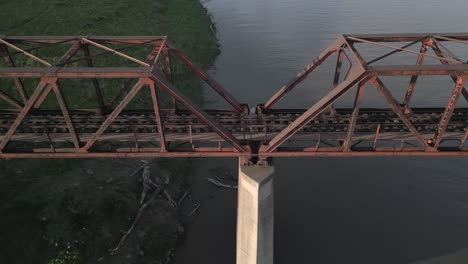 aerial view of long abandoned rusty old railway bridge over river