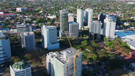 scenic orbiting aerial view of building construction site and crane amid developing philippine city