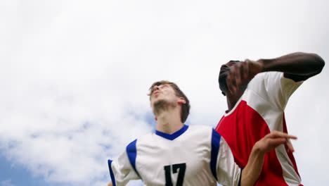 Two-football-players-jumping-to-strike-a-ball