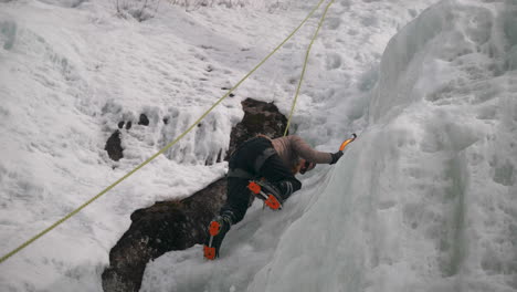 A-person-uses-crampons-and-ice-axe-to-climb-a-frozen-glacier