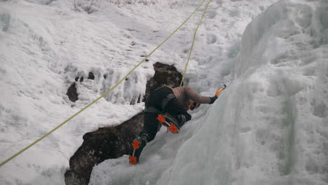 a person uses crampons and ice axe to climb a frozen glacier