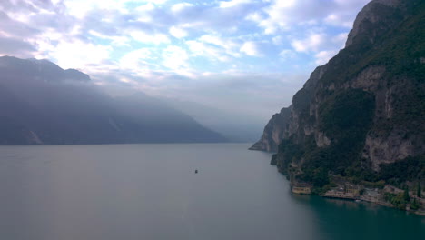 Toma-Aérea-De-La-Plataforma-Rodante-Que-Revela-La-Magnitud-Del-Lago-De-Garda-Con-Un-Bote-Grande-Que-Da-La-Sensación-De-Espacio