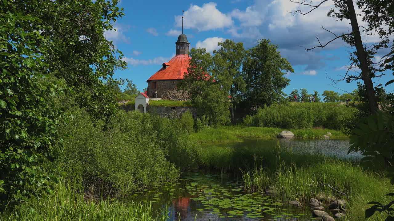 En gräsklädd och himmelsk utsikt över träden vid Museifästningen Korela i Ryssland.