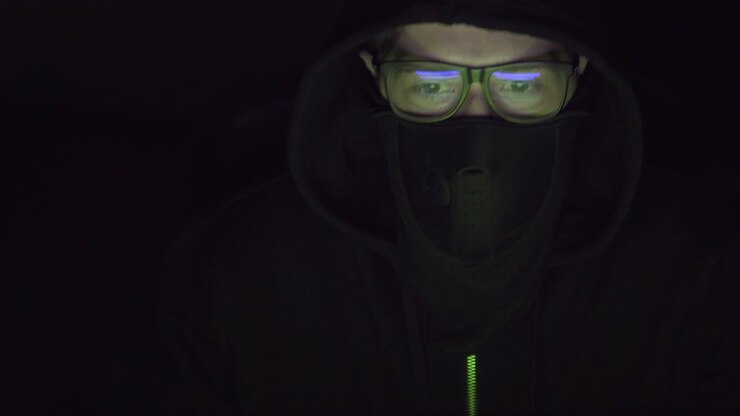 Video af en hacker med tildækket ansigt, mens han arbejder ved computeren