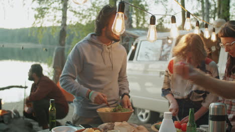 company of friends cooking dinner at campsite