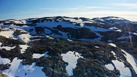 aerial ascent over folgefonna glacier range in norway, revealing snowy mountains, fjords and teal lakes during a bright summer day