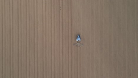 tractor seeding on a field in ireland - aerial top down
