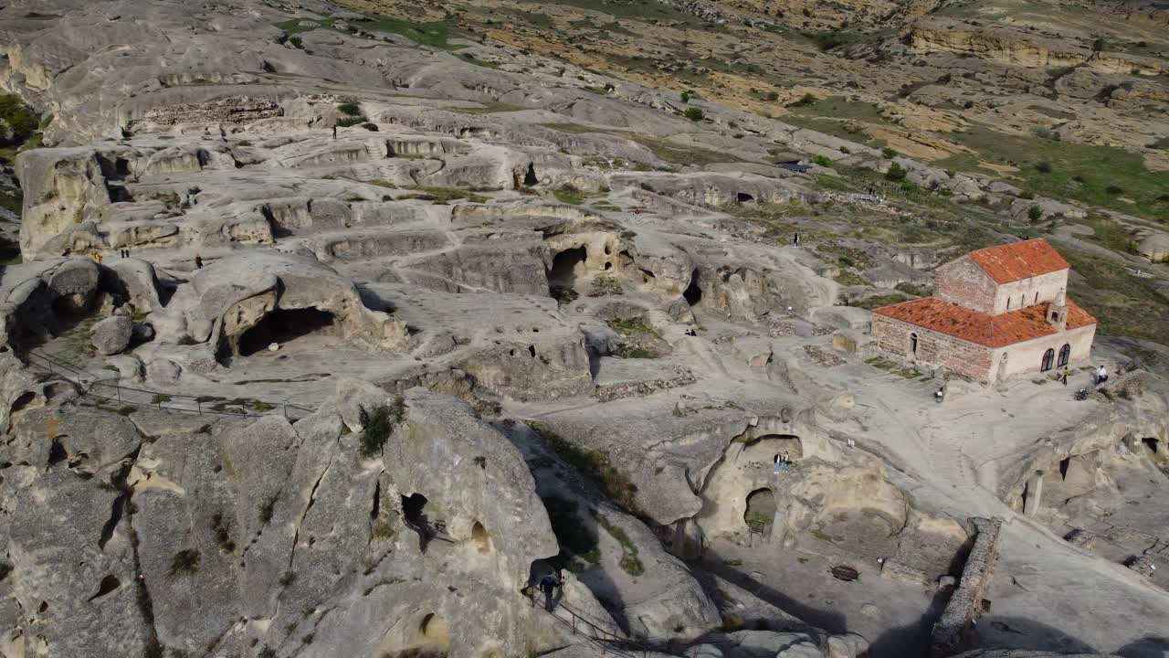Closer aerial of Uplistsikhe rock caves and tunnels carved into mountainside terrain