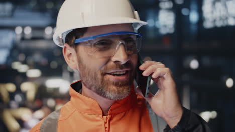 técnico feliz hablando por teléfono móvil en instalaciones de producción industrial en primer plano