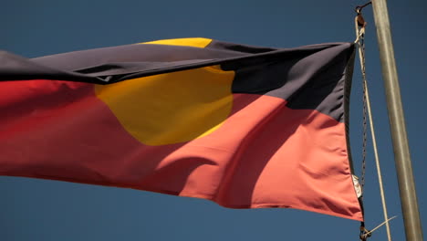 bandera aborigen australiana ondeando en la brisa bajo un cielo azul claro