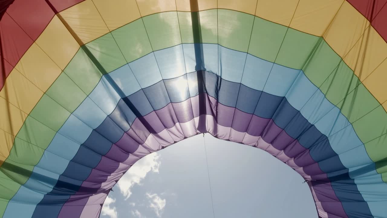 Tenda arcobaleno che si gonfia, levigando i pannelli e allargando l'apertura centrale sopra il terreno, mostrando i cavi.