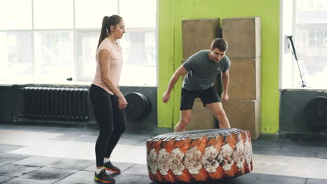 woman and man lifting tire in gym