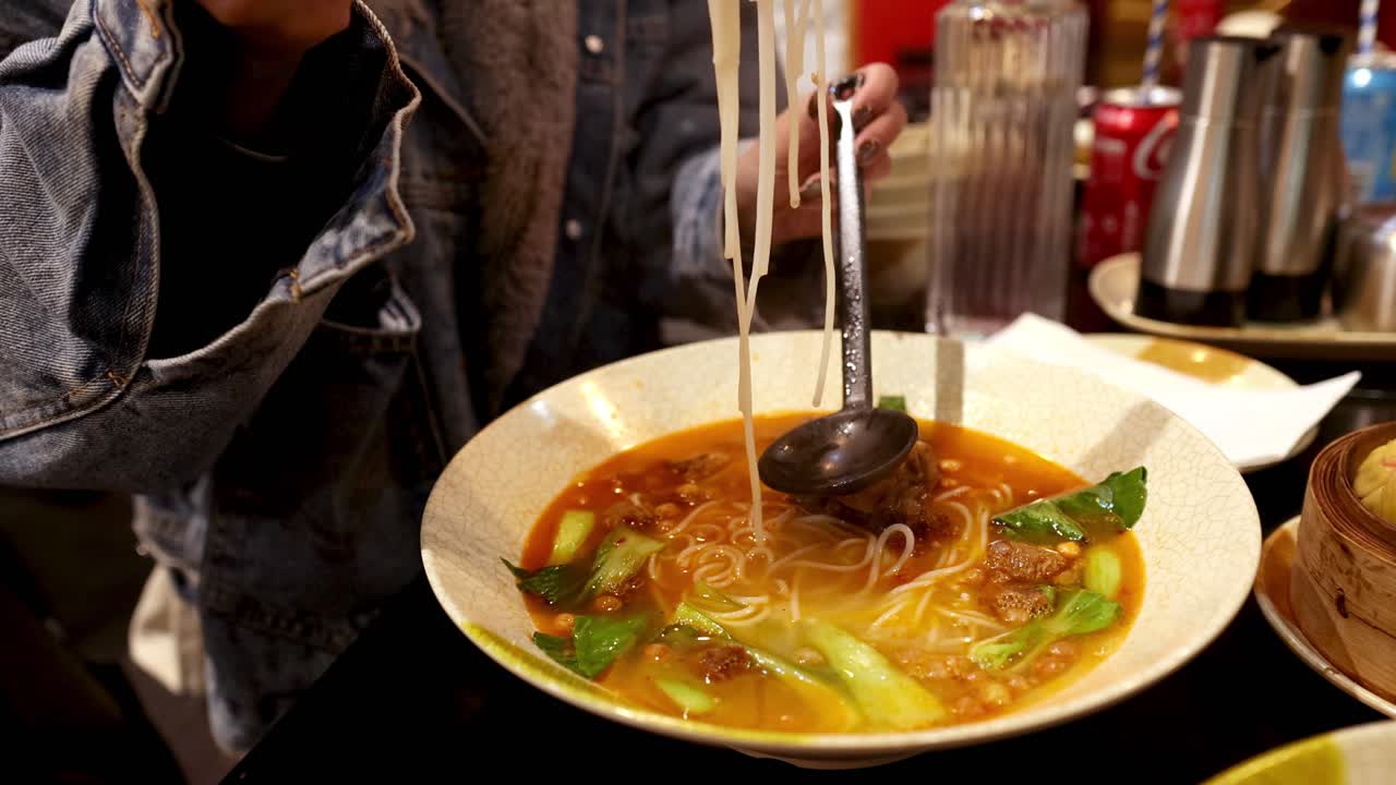 Person enjoying ramen with chopsticks and spoon