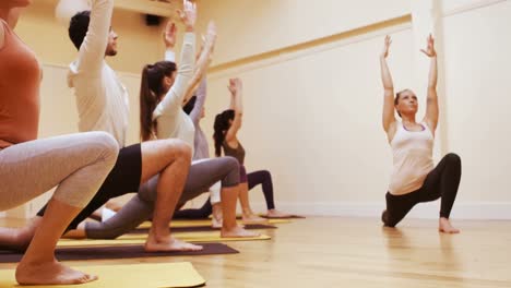 Trainer-assisting-group-of-people-with-stretching-exercise-