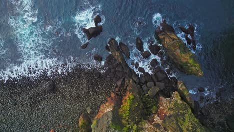 top down view of valahnukamol cliffs in iceland with beach waves crashing on rocky beach coast