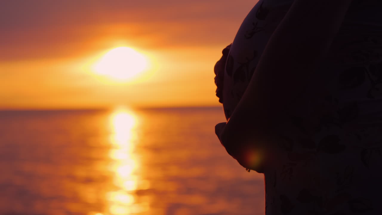 Belly Of A Pregnant Woman On A Background Of A Beautiful Sunset On The Sea Motherhood And Expecting 
