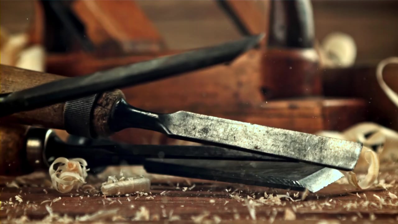 Stechbeitel fallen in Zeitlupe auf einen Holztisch