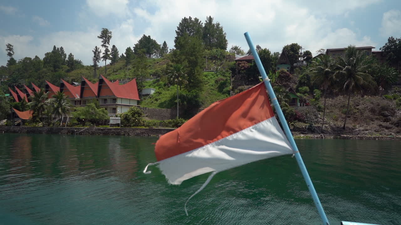 Rallentatore della bandiera indonesiana che sventola al vento su un traghetto che attraversa il Lago Toba a Sumatra Settentrionale