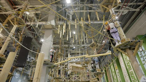 people navigating an indoor ropes course and adventure park