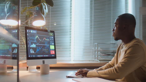 hombre afroamericano trabajando con datos financieros por la noche