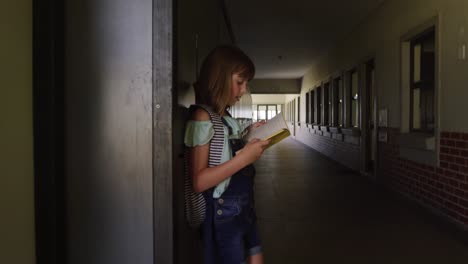 Girl-reading-books-in-the-school-corridor